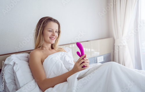 Young sexy woman in the bed holding in her hands a sex toy for adults photo