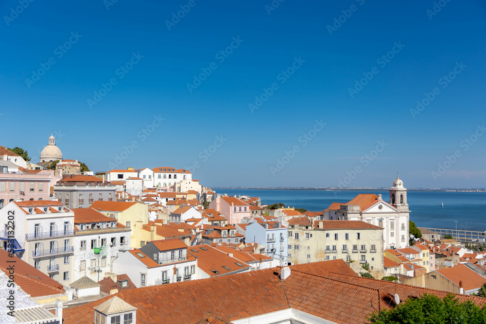 Typical cityscape of Lisbon, Orange brick roof top of building and housing in old town with harbor view, Narrow houses between small street in coastal of atlantic, Lisbon is capital city of Portugal.