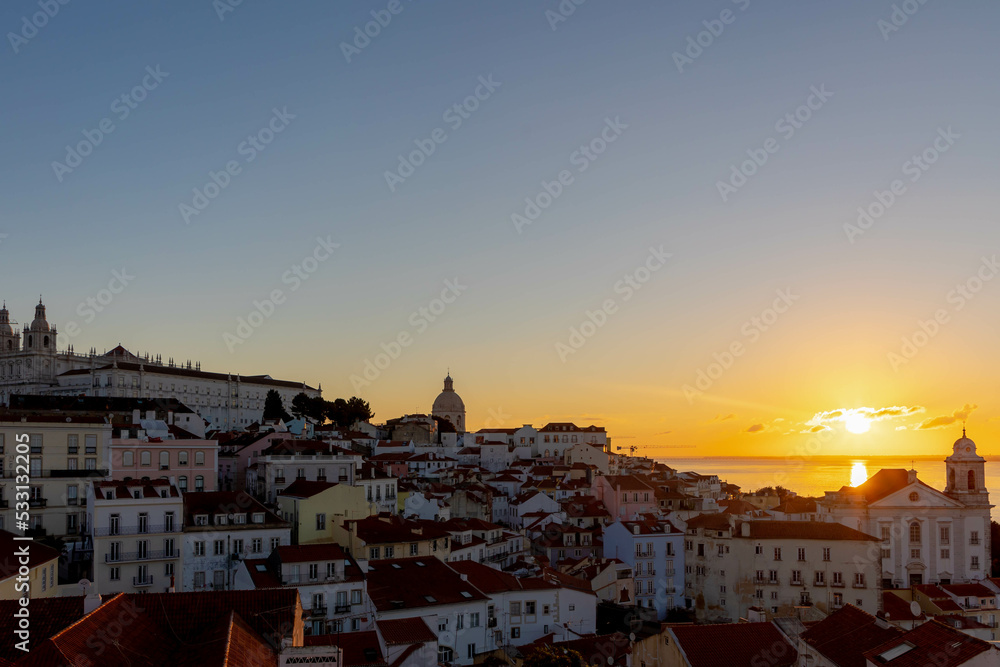 Typical cityscape of Lisbon, Sun rising in the morning with orange brick roof top of buildings and housing with harbor view, Narrow houses between small street in coastal of atlantic, Lisbon, Portugal