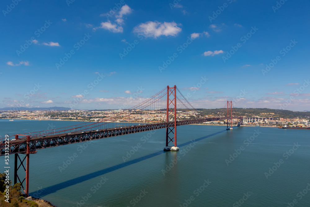 Naklejka premium The 25 de Abril Bridge (Ponte 25 de Abril) is a suspension bridge connecting the city of Lisbon capital of Portugal, to the municipality of Almada on the left (south) bank of the Tagus river.