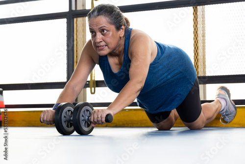 Woman strengthening her body by using the abdominal wheel 