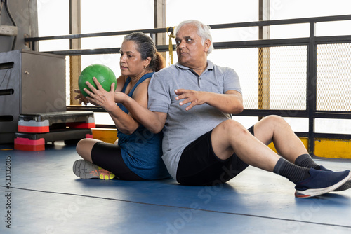 Men and woman exercising at health club with bell on floor 
