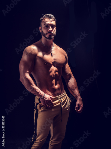 Shirtless muscular male bodybuilder in studio shot on black
