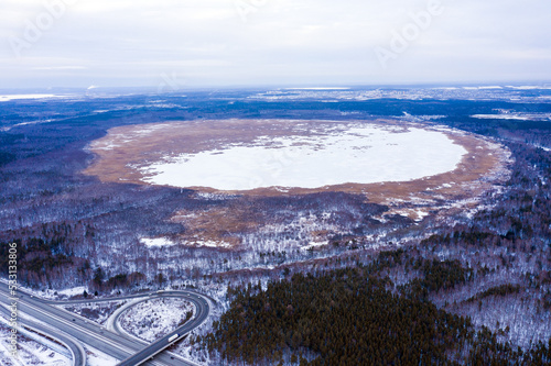 Top view of frozen lake in winter forest next to road junction