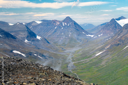 Vast Arctic landscape of Sarek National Park in Lapland,Sweden, viewed from the top of Naite mountain. Outdoor adventure in Laponia. Hiking in remote arctic wilderness. Sunny day of arctic summer.