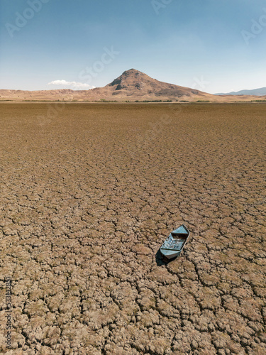 Fotografía Abandoned row boat on cracked soil on lake bed dried up due to global warming an