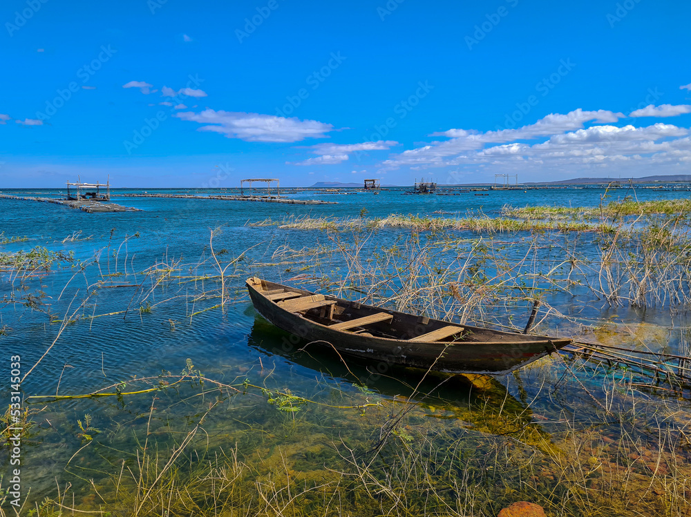 Obraz premium Wooden boat moored in a lake with captive fish farming structure