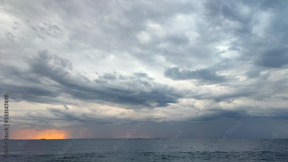 Movement of large gray rain clouds, falling rain and yellow-orange spot of rising sun on horizon in sea. Timelapse. Cloudy overcast sea weather. Epic panorama landscape. Beautiful natural background Movement of large gray rain clouds, falling rain and yellow-orange spot of rising sun on horizon in sea. Timelapse. Cloudy overcast sea weather. Epic panorama landscape. Beautiful natural background