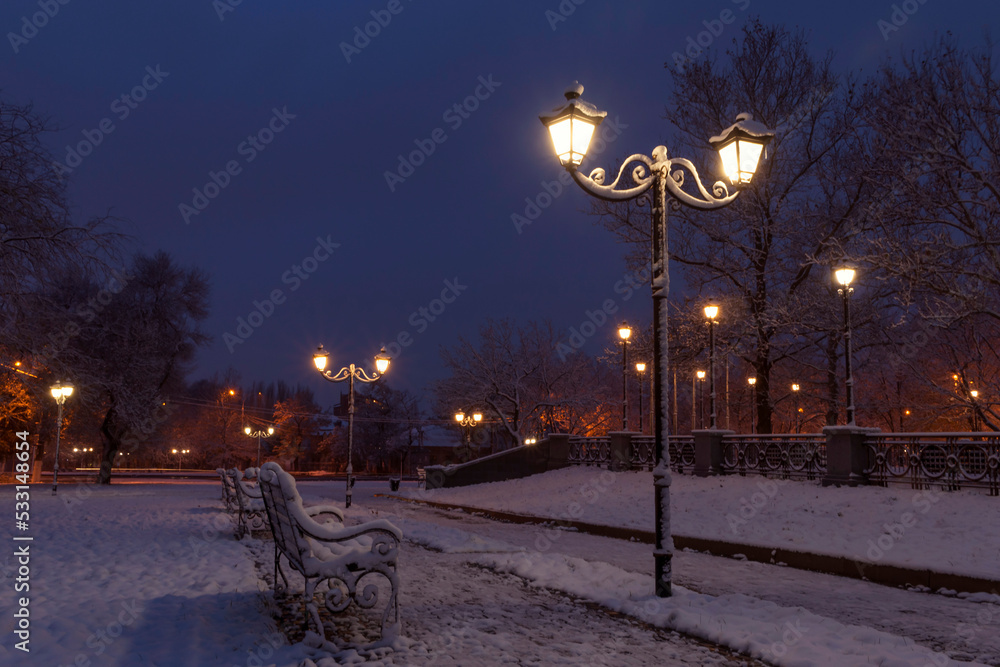 lantern and bench in park at winter night