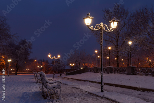 lantern and bench in park at winter night