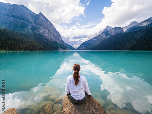 person sitting on a rock looking out over lake louise in banff national park