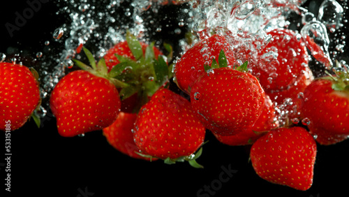 Strawberry fruit falling down and splashing underwater.