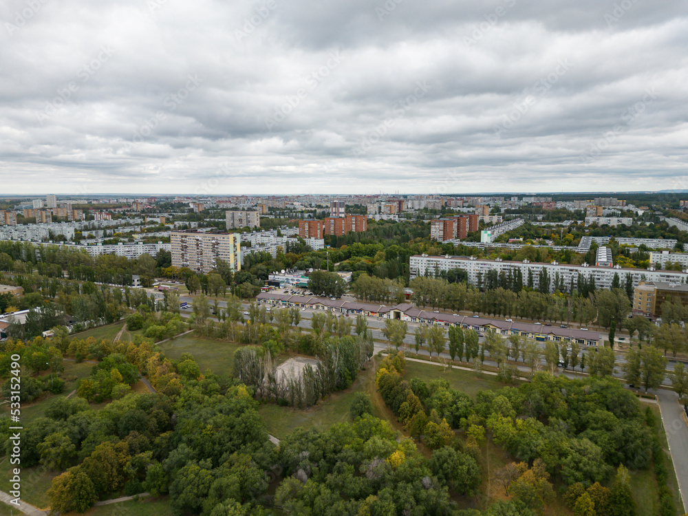 Panoramic view from the drone of a walking park near residential buildings. Urban landscape, bird's-eye view from the park. Cloudy weather over the city.