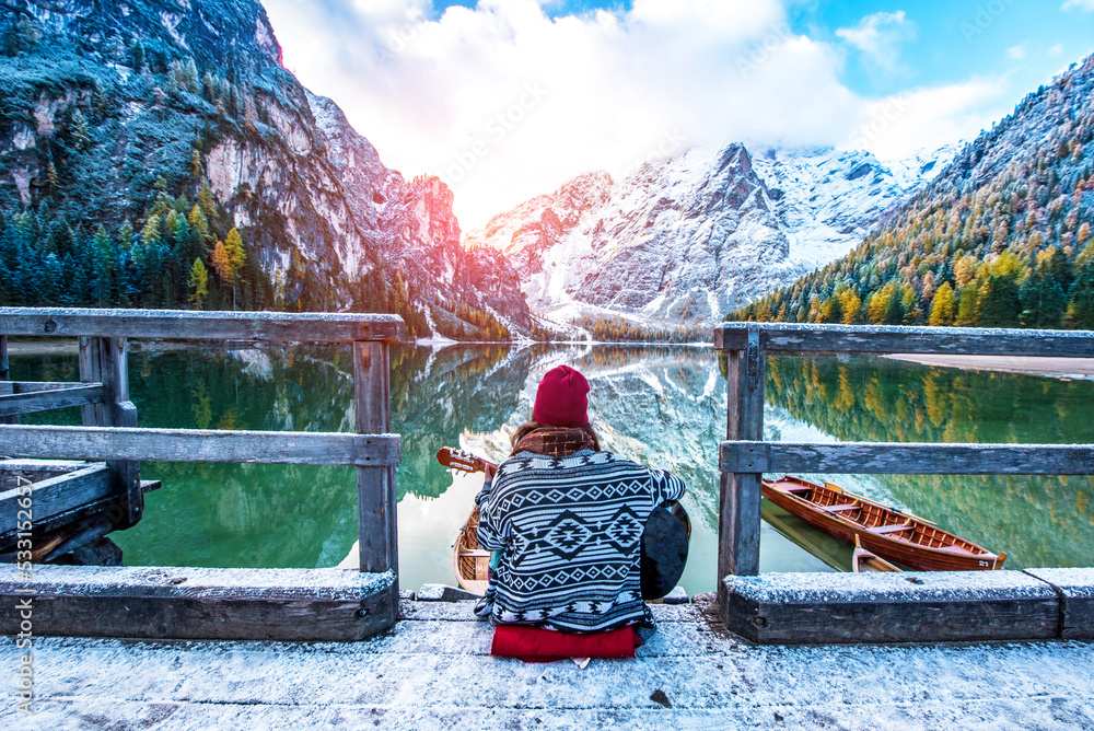 Amazing fascinating magical autumn winter landscape with a girl playing guitar over a lake on Fanes-Sennes-Braies natural park in the Dolomites in South Tyrol, Alps, Italy