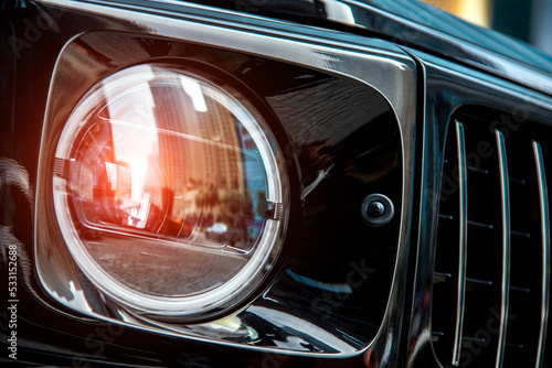 Obraz na płótnie Blurry reflection of Dubai skyscrapers in the headlight of a luxury black car w salonie
