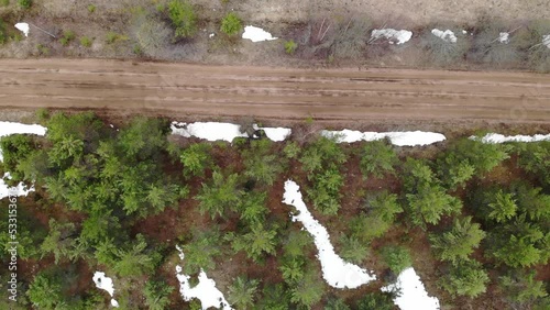 Country gravel road at winter or spring. Snow and green trees. Aerial drone view. Flying over. View from top down. High quality 4k footage photo