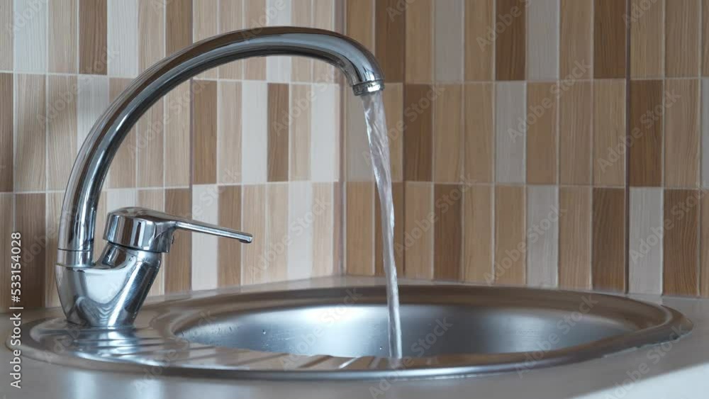 From the tap is flows water. Water pours in a strong stream from the tap in kitchen From the tap is flows water. Water pours in a strong stream from the tap in kitchen