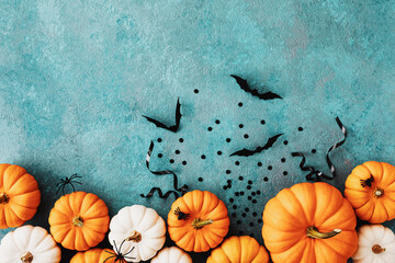 Halloween holiday card with party decorations of pumpkins and bats on blue table top view. Happy halloween greeting poster in flat lay style.