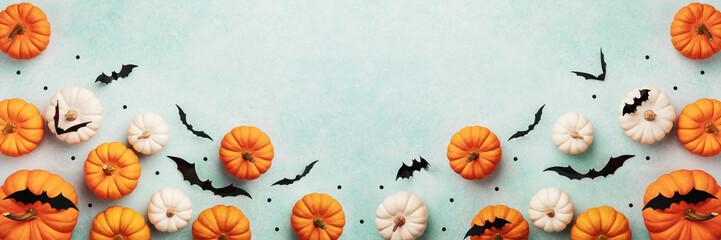 Halloween frame with party decorations of pumpkins and bats on blue background from above. Happy halloween card in flat lay style.