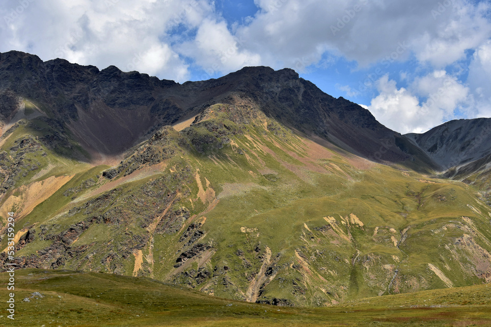 mountain panorama view with forest on the slopes of the mountains. Dramatic, high and beautiful Alps. Beautiful sky over the mountains. The rays of the sun and the road. Travel and challenge. Landscap