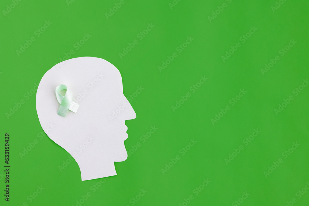 Brain paper cutout with green ribbon on green background with copy space. Mockup for world mental health day Brain paper cutout with green ribbon on green background with copy space. Mockup for world mental health day