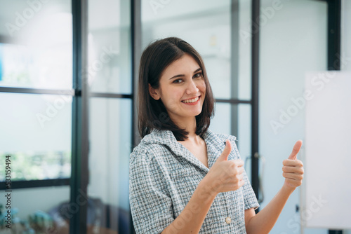 Free Download Portrait of a businesswoman giving the thumbs up at the workplace. - GFXLoad