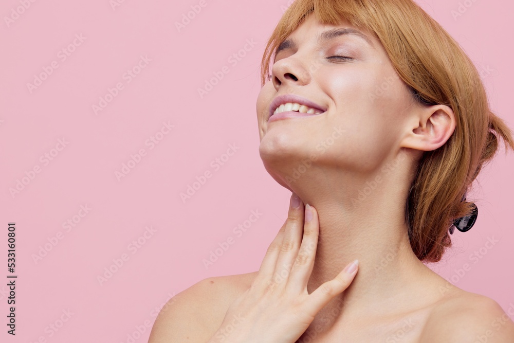 a close horizontal beauty photo on a pink background of a nice girl with her hair pinned up from behind, smiling pleasantly with her eyes closed, gently touches her neck with her hand a close horizontal beauty photo on a pink background of a nice girl with her hair pinned up from behind, smiling pleasantly with her eyes closed, gently touches her neck with her hand