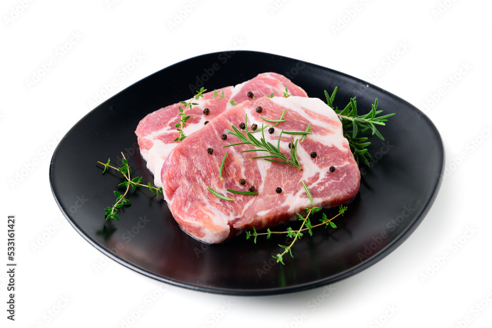 Pieces of pork meat with rosemary and thyme leaves on black dish on white background, Pieces of pork meat with rosemary and thyme leaves on black dish on white background,