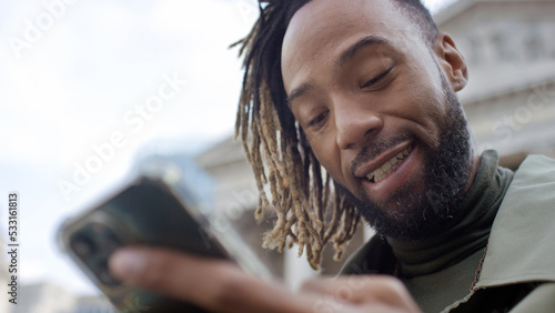 Close shot of handsome man reacting positively to something on his phone outdoors in the city