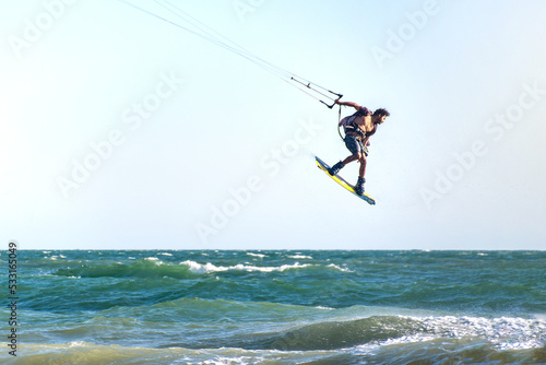 Young man kite boarder jumps over the sea at sunset. Selective focus.