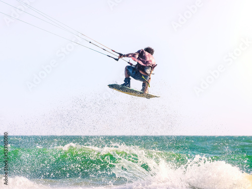Young man kite boarder jumps over the sea at sunset. Selective focus.