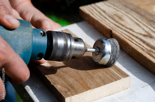 Drill with a wire brush. Woodworking outdoors