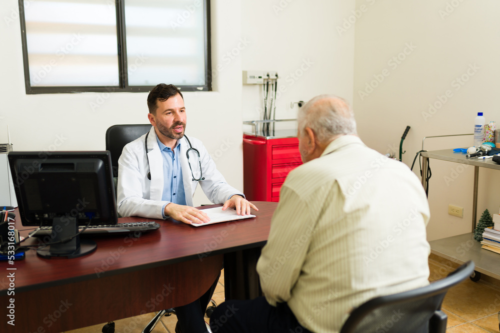 Obraz premium Concerned doctor seen from behind at his office with an elderly patient