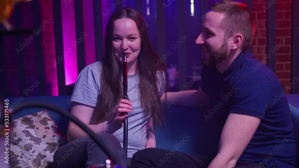 young cute couple are sitting on the couch in the hookah bar. flirt, smile and smoke a hookah young cute couple are sitting on the couch in the hookah bar. flirt, smile and smoke a hookah