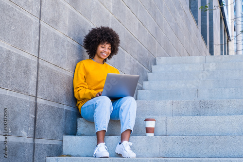 Fototapeta Happy young african businesswoman worker student relaxing sit on the stairs of the city