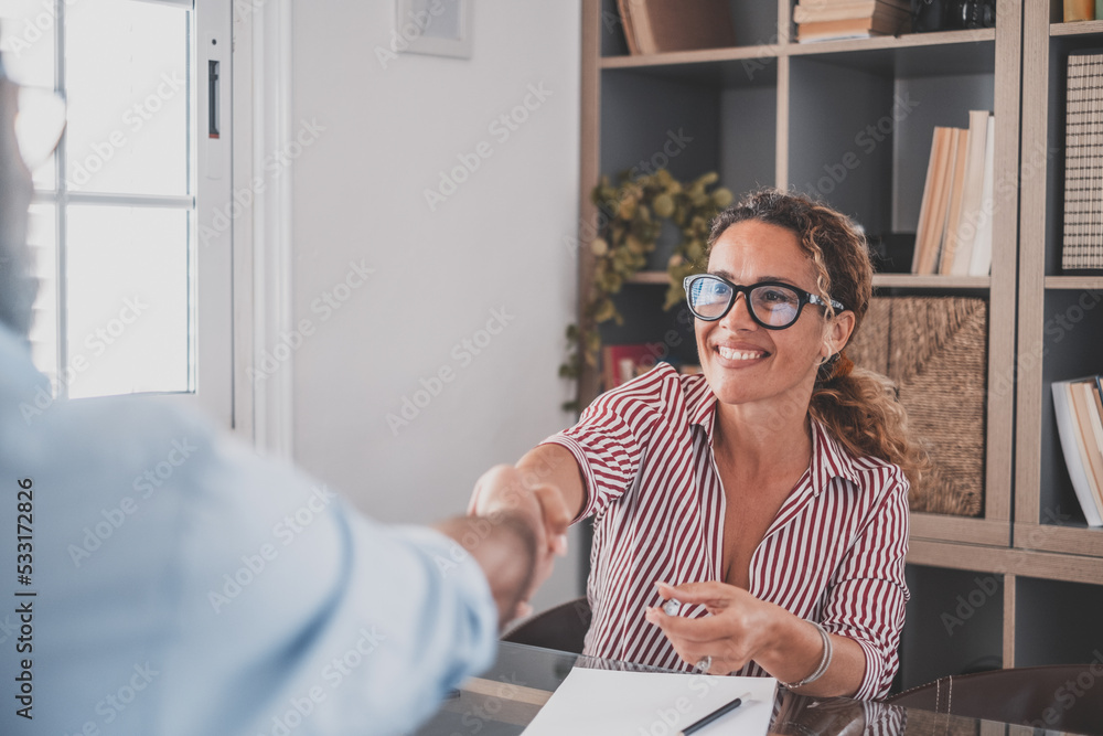 Smiling caucasian female hr manager handshake hire male candidate at job interview make good first impression, happy mixed race client shake hand of bank broker, respect, business agreement concept. - obrazy, fototapety, plakaty 