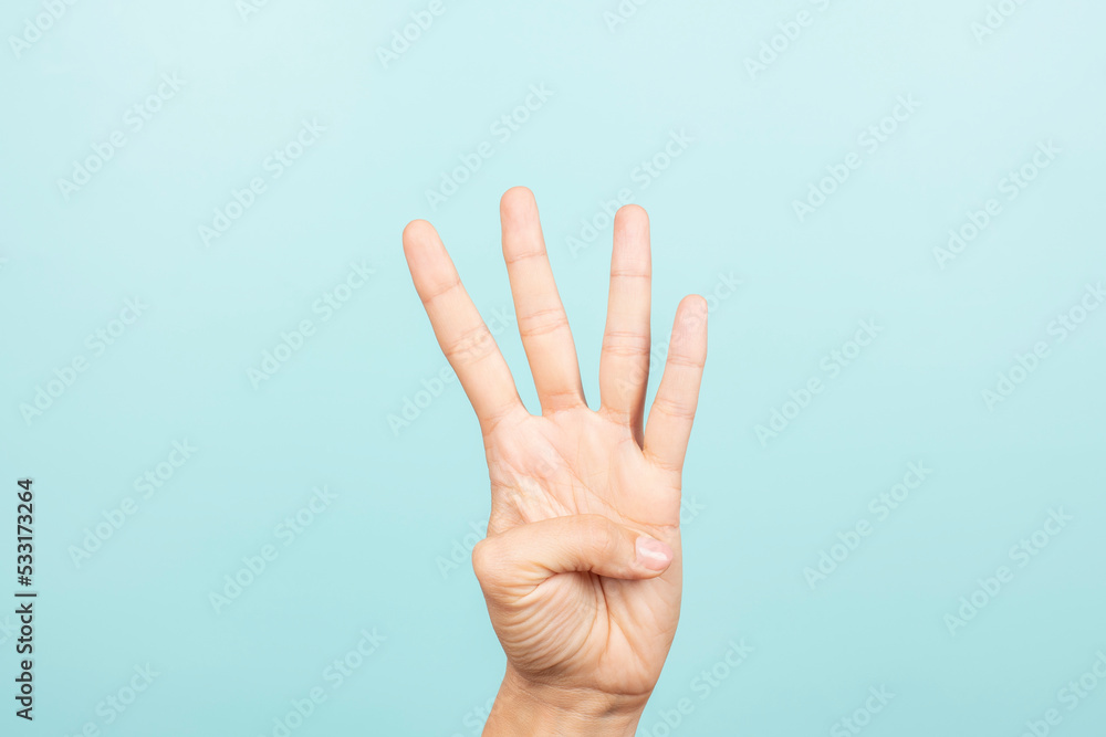 Hand gesture. Female hand shows number four. Woman hand pointing up with three fingers on light blue background