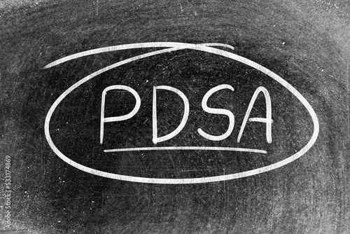 White chalk hand writing in word PDSA (Abbreviation of plan do study act) on blackboard background photo