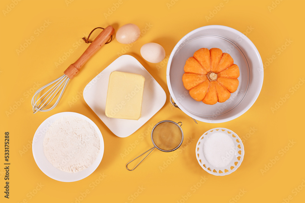 Pumpkin pie ingredients and baking tools on yellow background