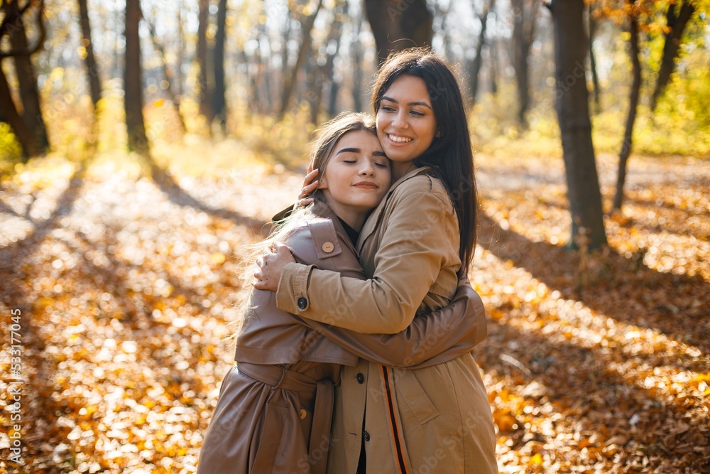 Two girls friends walking together in autumn park Two girls friends walking together in autumn park