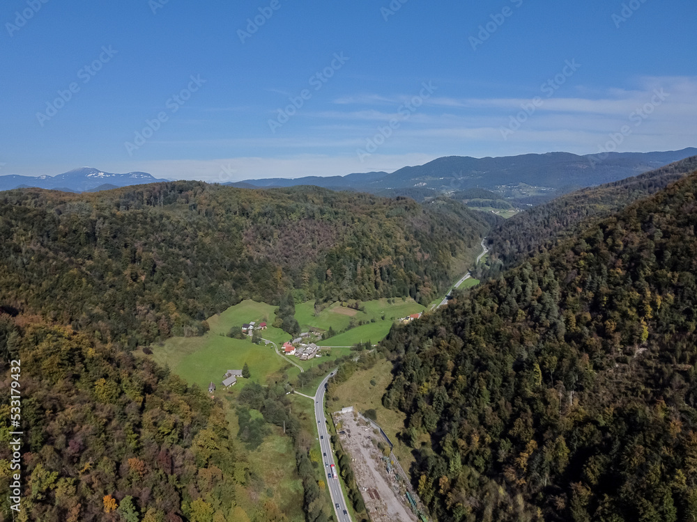 Aerial drone view road between hills with forest