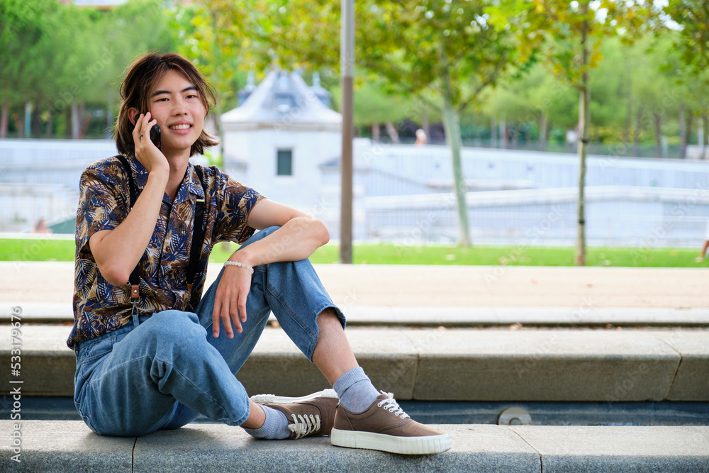 Young Asian man talking on the smartphone at street. Young Asian man talking on the smartphone at street.