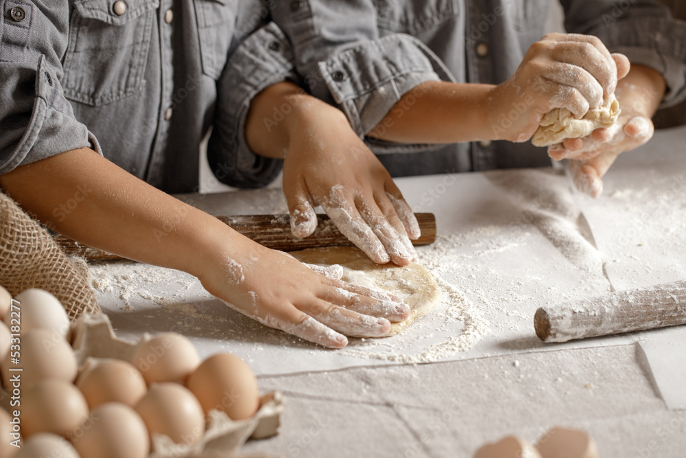 Fototapeta premium Children’s hands, flour and dough. Boys are preparing a dough for home baking. Concept of home cooking with organic and natural ingredients. Zero waste concept