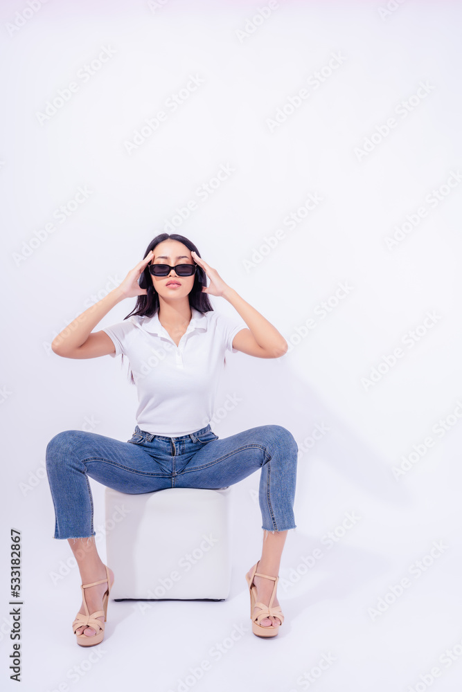 Beautiful young asian woman in Jeans High heel Collar shirt sitting on sofa cube isolated on white background in Studio Attractive girl wear sunglasses Full length of Asia female posing confident Beautiful young asian woman in Jeans High heel Collar shirt sitting on sofa cube isolated on white background in Studio Attractive girl wear sunglasses Full length of Asia female posing confident