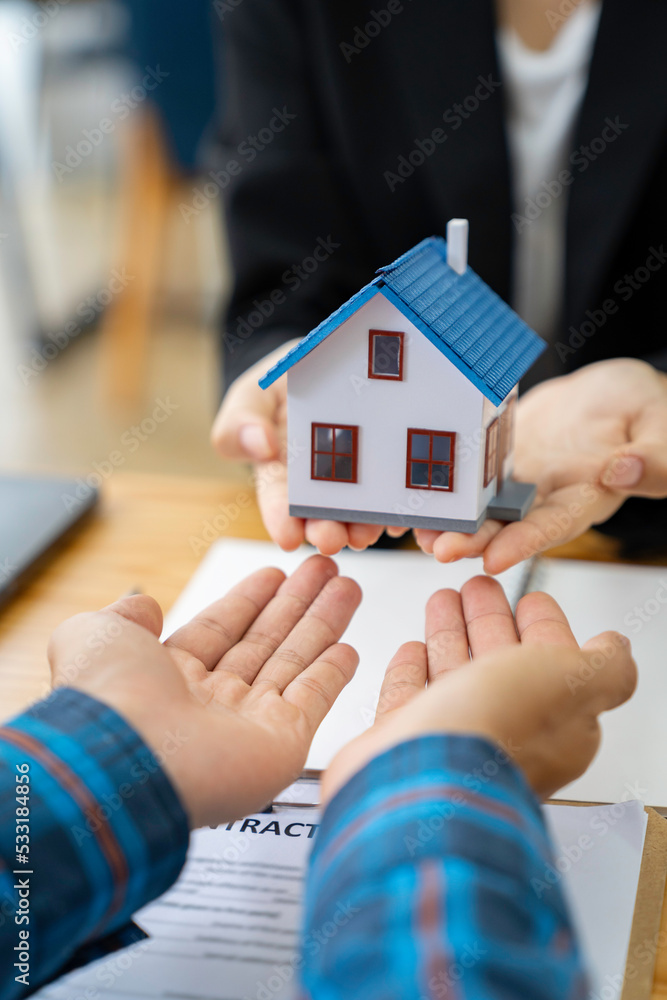 real estate agent salesman holds a model of a house and sends it to