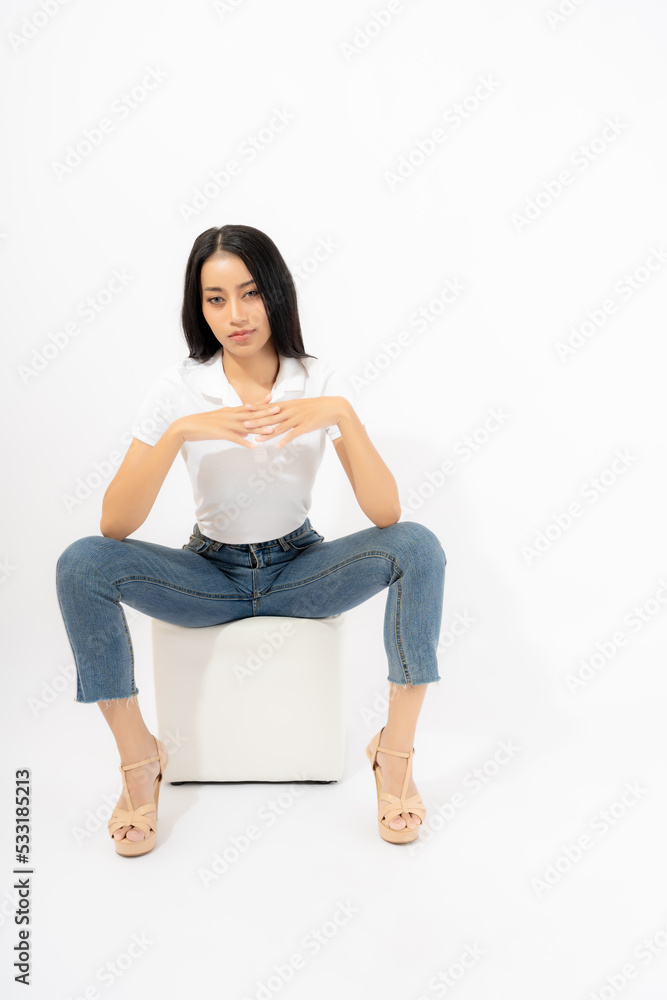 Beautiful confident young asian woman in jeans high heel collar shirt sitting on chair cube isolated on white background Studio shot Attractive girl looking at camera Full length of Asia female posing Beautiful confident young asian woman in jeans high heel collar shirt sitting on chair cube isolated on white background Studio shot Attractive girl looking at camera Full length of Asia female posing