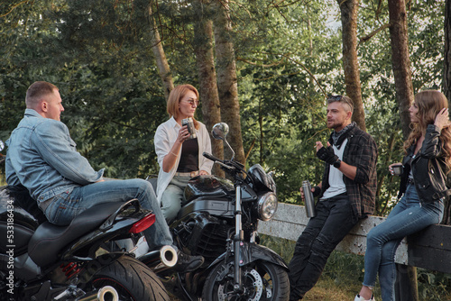 A company of friends travel together on motorcycles, stopped at the roadside, have fun and drink tea