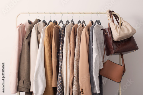female autumn clothes on hangers in white room