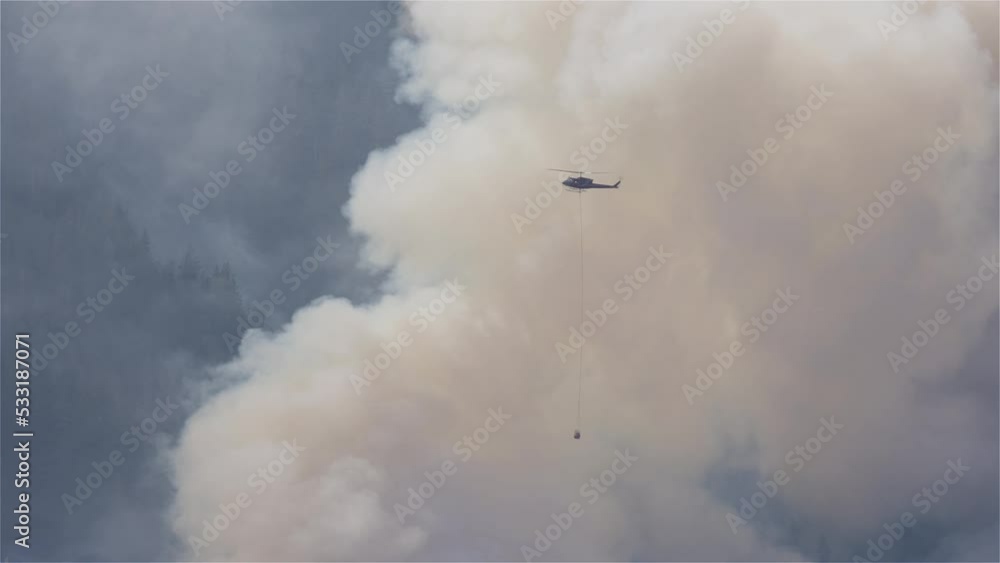 Wildfire Service Helicopter flying over BC Forest Fire and Smoke on the mountain near Hope during a hot sunny summer day. British Columbia, Canada. Natural Disaster. Slow Motion Wildfire Service Helicopter flying over BC Forest Fire and Smoke on the mountain near Hope during a hot sunny summer day. British Columbia, Canada. Natural Disaster. Slow Motion