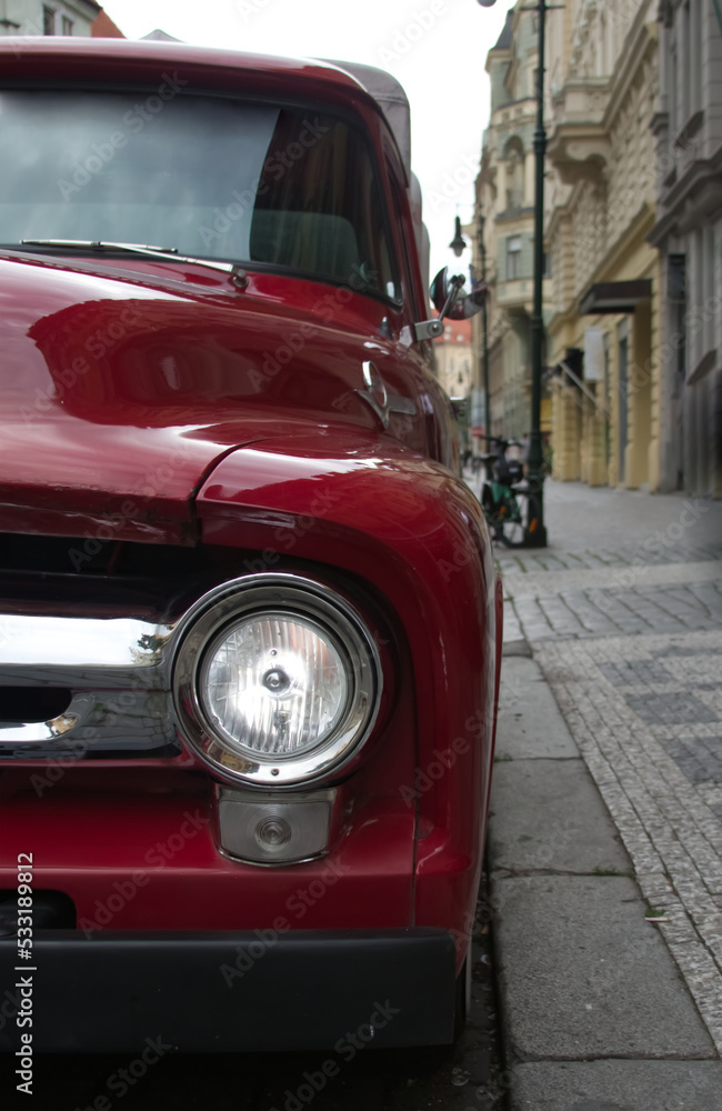 Red retro car parked on a paved European street close-up